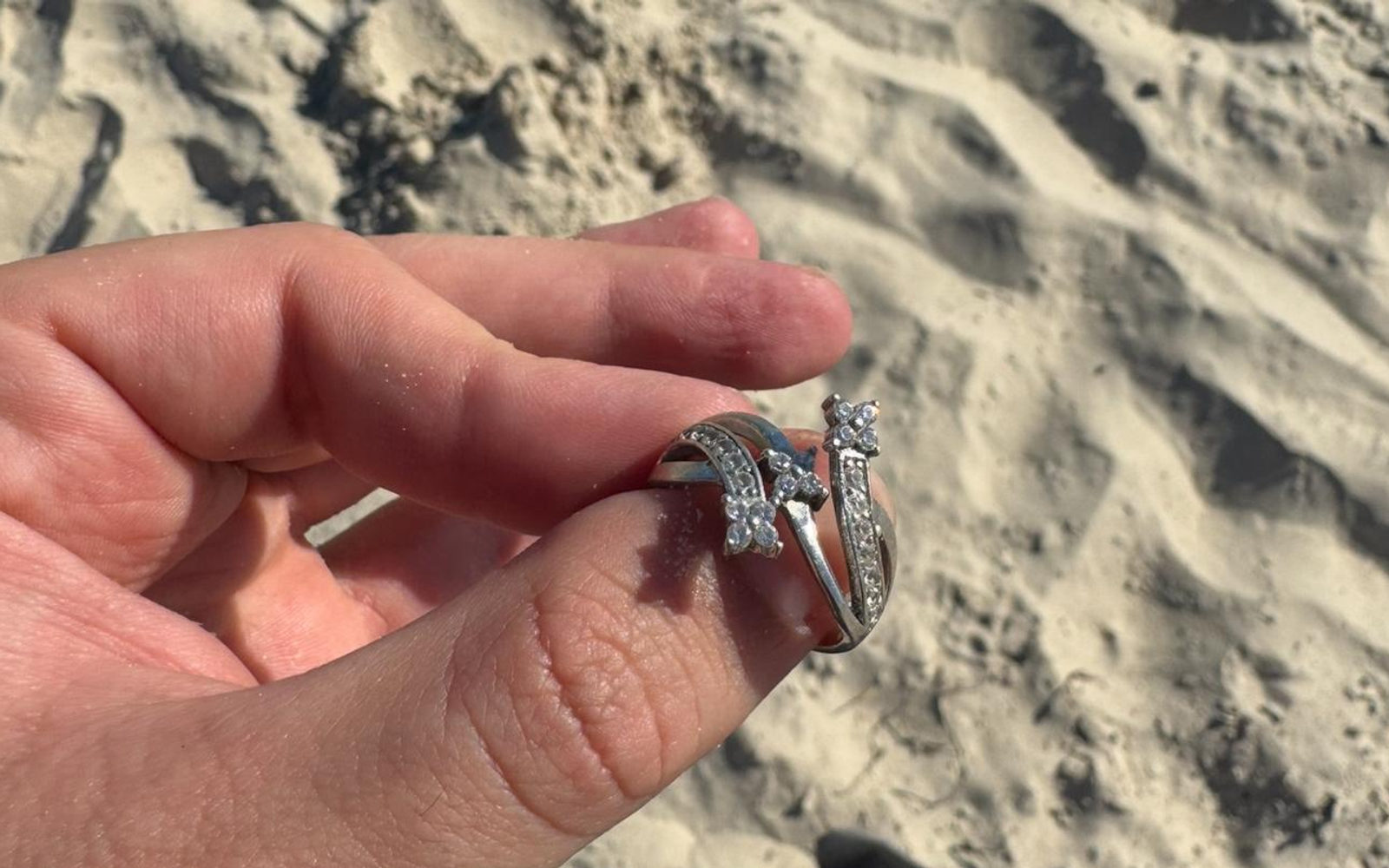 Recovered diamond rings held in a hand above the sand